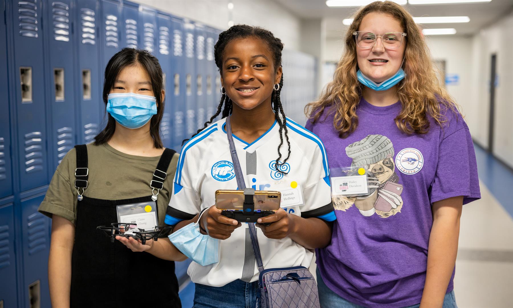 Three girls smile while holding a drone and controller